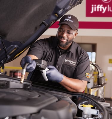 Technician working under the hood of a car.