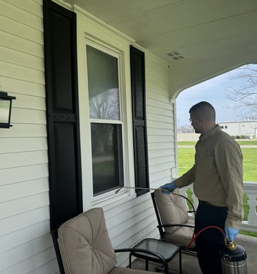 Pest control technician spraying around window