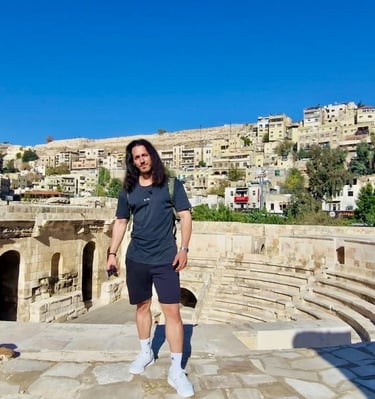 Viajero posando en el antiguo teatro romano de Ammán, Jordania, con la ciudad y colinas al fondo, dí