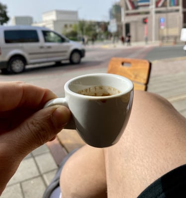 Persona disfrutando un café espresso en una terraza de Tirana, Albania, con vista urbana y ambiente 