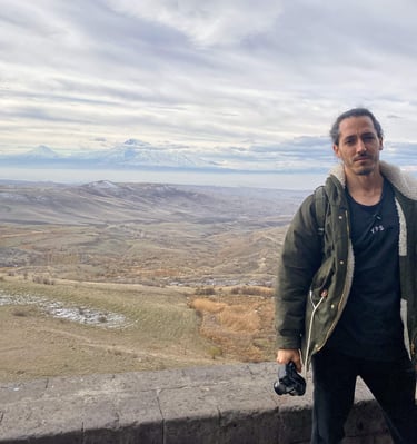 Persona posando con el monte Ararat al fondo en Armenia, paisaje montañoso y cielo nublado