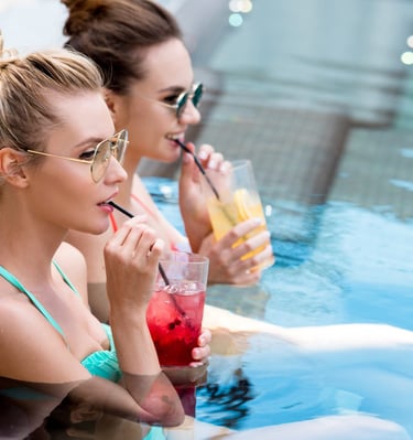 Two women sipping cocktails in the pool during a Vegas Pool Party Crawl