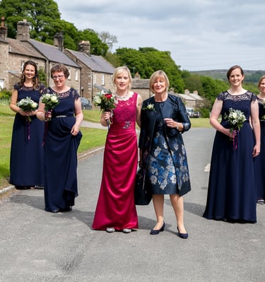 Bride with her bridesmaids. Mother is standing next to bride. Whole group are in a dart formation.