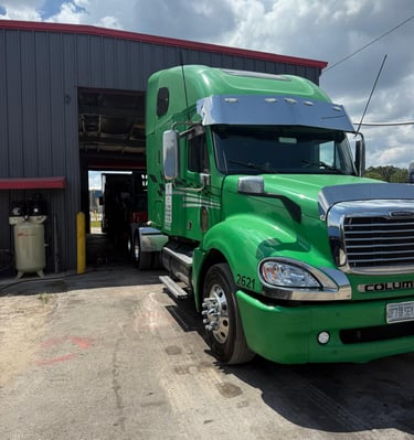 a green semi truck parked in front of a building