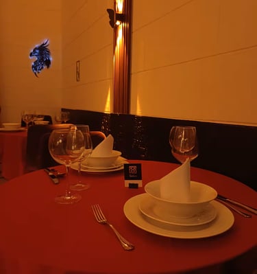 Elegant fine dining table setting with red tablecloth, wine glasses, and white dinnerware.