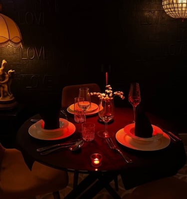 Romantic candlelit dinner table for two with wine glasses and elegant lamp lighting.