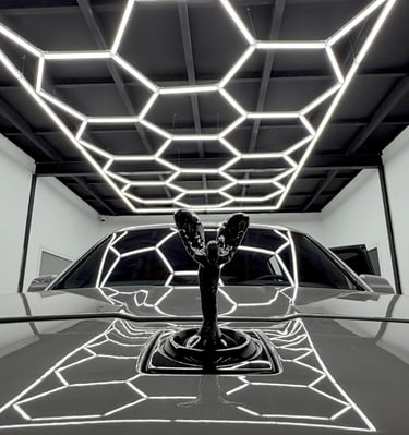 Rolls-Royce Spirit of Ecstasy hood ornament reflecting hexagonal LED garage lights.
