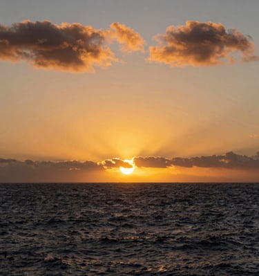 A stunning sunset over a modern luxury home overlooking the Kona coastline.