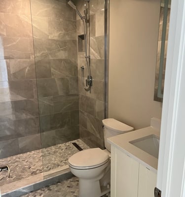Modern bathroom featuring a glass walk-in shower with gray porcelain tiles and a white vanity.