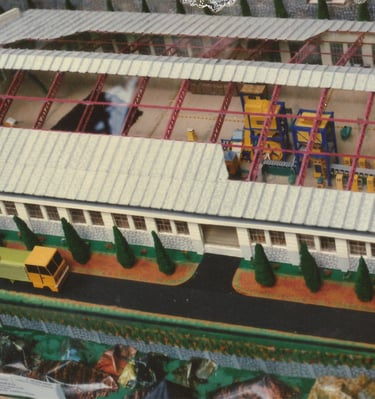 Scale model of an industrial warehouse facility featuring a cutaway roof and interior machinery 1975