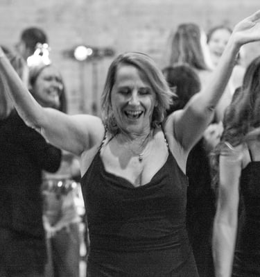 A cheerful woman dancing with arms raised during a gala in downtown Austin