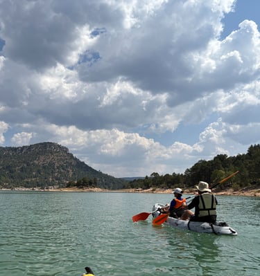 Piragua remando en el embalse de la Toba con un cielo nuboso precioso y montañas y vegetacion al fon