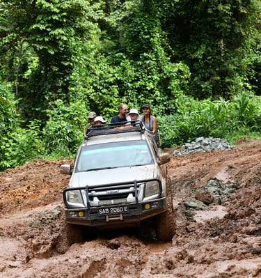 A group of people sitting at the back of the 4x4 truck on their way to the village