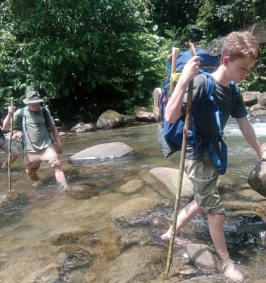 a man with a backpacker walking through a stream