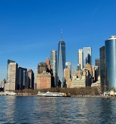 Panoramic view of the Lower Manhattan skyline and One World Trade Center from the water on a clear day.