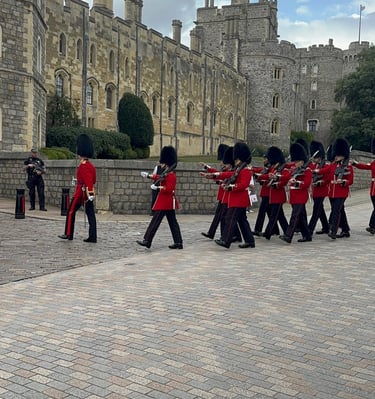 King's Guard in red tunics and bearskin hats marching at Windsor Castle.