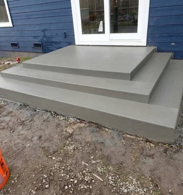 Newly poured concrete steps leading to a sliding glass door on a blue house, showcasing professional