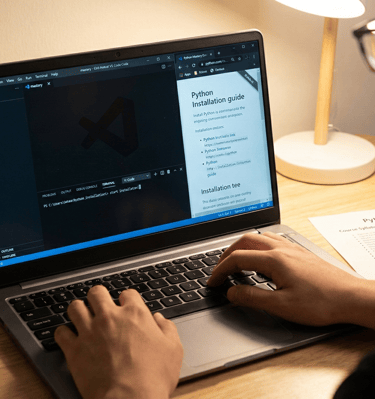 A close-up, warm-toned photograph focusing on a beginner's workstation. A single laptop screen displ