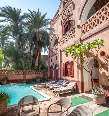 A courtyard featuring a private swimming pool, sun loungers, and tropical palm trees in Egypt.