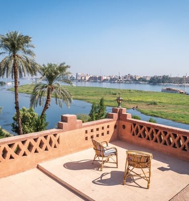Luxury terrace balcony overlooking the Nile River in Egypt with palm trees and cruise ships.