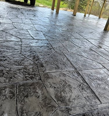 Dark gray stamped concrete patio with a glossy wet-look sealer and flagstone pattern.