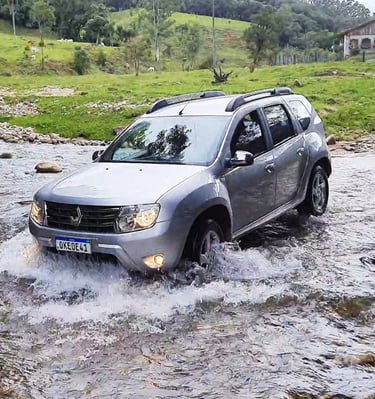 Renault Duster atravessando rio com pedras durante aventura outdoor em família