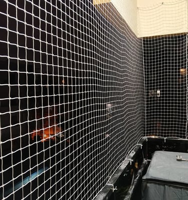 Evening view of a balcony secured with tight safety nets, lights glowing softly.