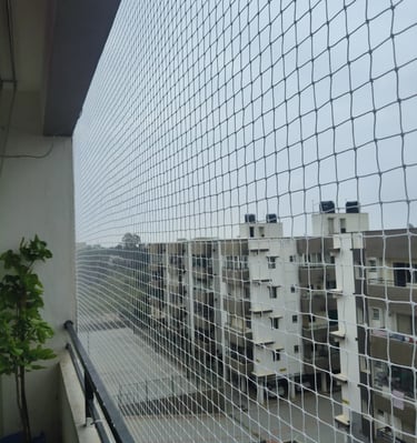 Balcony corner protected by a pigeon net, capturing sunlight filtering through the mesh.
