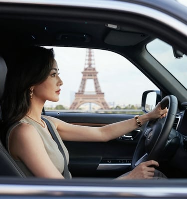 A confident female driver wearing a subtle pink scarf, smiling warmly at the camera.