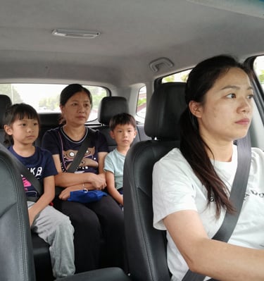 A smiling female driver opening the car door for a woman passenger in soft natural light.