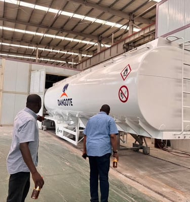 Two men inspecting a white Dangote fuel tanker trailer inside our industrial warehouse facility.