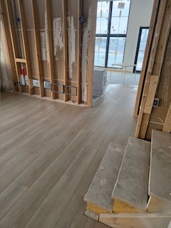 Modern light oak luxury vinyl plank flooring installed in a home under construction.