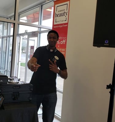 DJ Aaron Harris posing next to his DJ setup inside of Ulta Beauty for a promotional event.