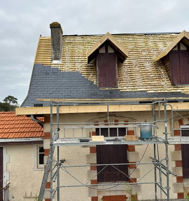 Installation professionnelle de toiture en ardoise sur une maison avec échafaudage et lucarnes.