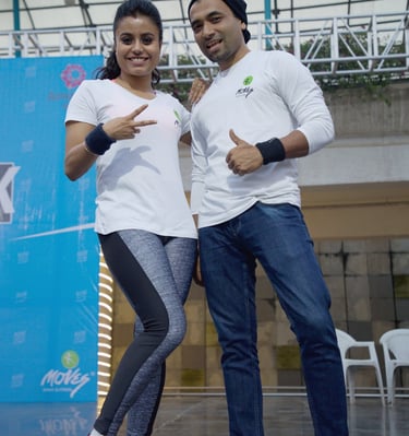 Smiling man and woman in white athletic shirts posing at an outdoor fitness event.