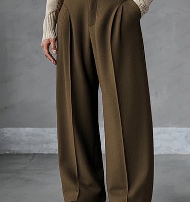 A person wearing olive green high-waisted wide-leg wool trousers with pleats and brown leather loafers.
