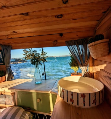 Aménagement van vintage avec vue sur l'océan en Bretagne, intérieur bois et décoration artisanale.