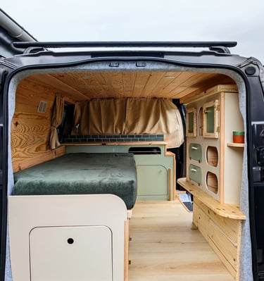 Aménagement intérieur van sur-mesure en bois clair avec lit peigne et rangements vintage par Pinbeur