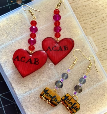  two pair of earrings, one w. beads and red "ACAB" heart charms and one w. mini metrocard charms