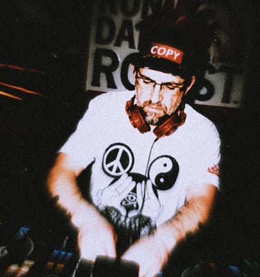Dacarter DJ wearing headphones mixing music on a controller with a laptop at a club event.