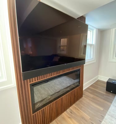 Finished basement with built-in shelving, electric fireplace, and TV above