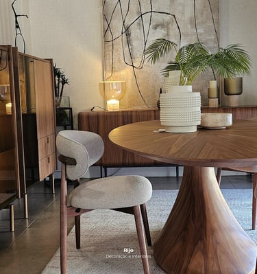 Modern dining room featuring a round walnut table and stylish grey upholstered chair with abstract wall art.