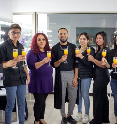 Un grupo diverso de amigos sonriendo y levantando copas de mimosas en un estudio de maquillaje