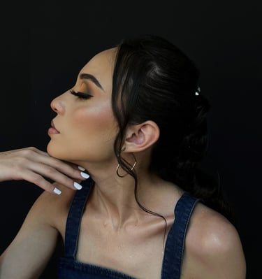 Perfil lateral de una mujer con sombra de ojos de atardecer y un top de mezclilla sobre un fondo neg