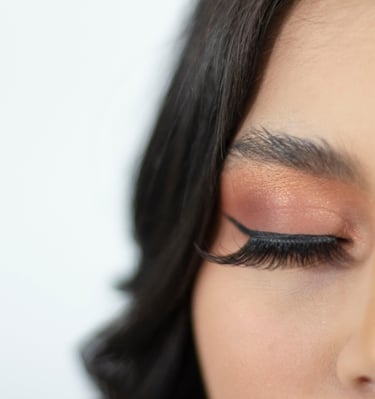 Primer plano de una mujer con sombra de ojos color bronce, delineador de ojos negro y pestañas posti
