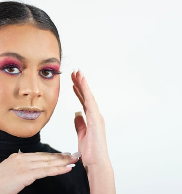 Mujer joven que usa una sombra de ojos rosa intensa y un lápiz labial plateado brillante para lograr