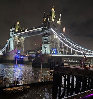 Night view of the illuminated Tower Bridge over River Thames in London with city lights.
