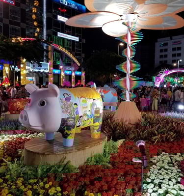 Festive pig statue with floral art at a vibrant night market display for Lunar New Year celebrations.