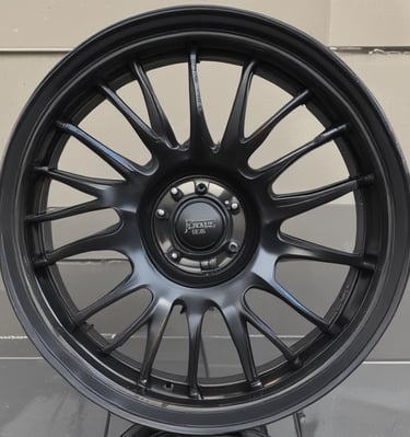 Close-up of a freshly powder-coated set of custom car wheels gleaming under shop lights.