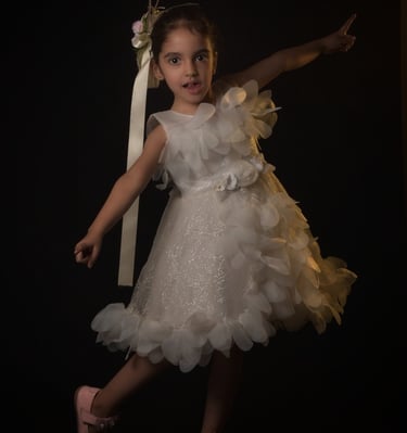 Young girl in a beautiful white flower dress striking a pose with pink shoes. Wonderpose photograph